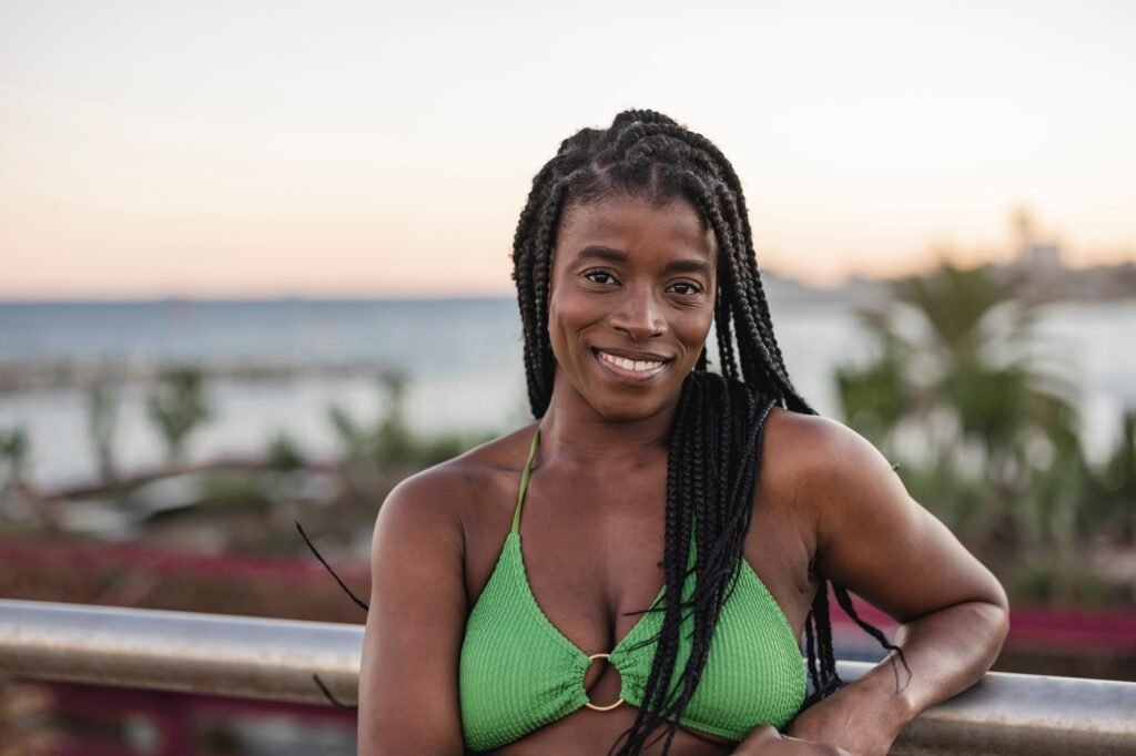 Close up portrait of a smiling african american young female with braided hair near the sea