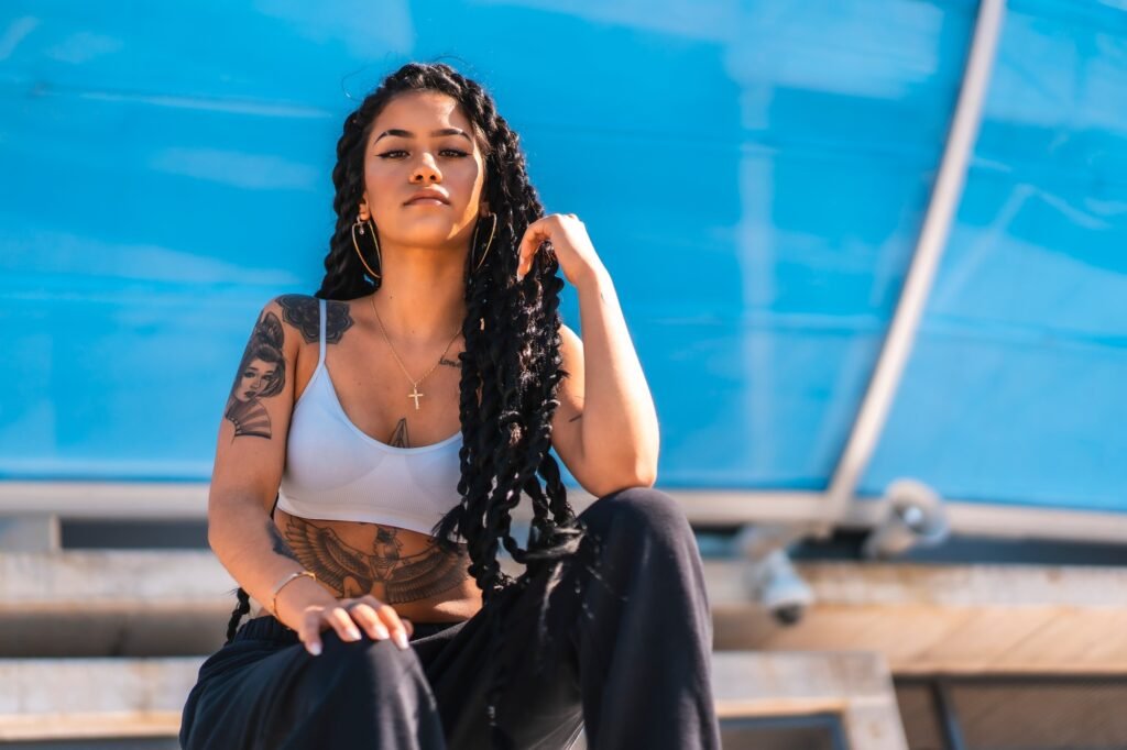 Young black woman with long braids and tattoos, looking at camera, copy space
